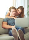 Couple, laptop and hug on home sofa while on internet for remote work or streaming movies. A man and woman together in a Royalty Free Stock Photo