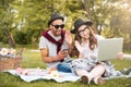 Couple with laptop listening to music from smartphone in park Royalty Free Stock Photo