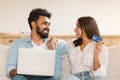 Couple laughing on couch, using laptop and woman holding blue card Royalty Free Stock Photo