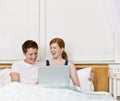 Couple laughing and using laptop in bed Royalty Free Stock Photo