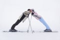 Couple leaning towards each other standing on skis side view