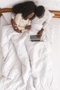 Afro couple sitting in bed with laptop, top view Royalty Free Stock Photo