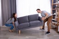 Couple lifting sofa in living room Royalty Free Stock Photo