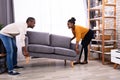 Couple Lifting Sofa In Living Room Royalty Free Stock Photo