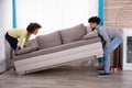 Couple Lifting Sofa In Living Room Royalty Free Stock Photo