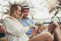 Couple listening music with a tablet sitting in park Royalty Free Stock Photo