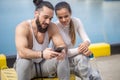 Couple listening to music together using one earphones sitting on pier Royalty Free Stock Photo