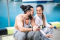 Couple listening to music together using one earphones sitting on pier Royalty Free Stock Photo