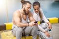 Couple listening to music together using one earphones sitting on pier Royalty Free Stock Photo