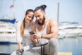 Couple listening to music together using one earphones sitting on pier Royalty Free Stock Photo