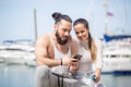 Couple listening to music together using one earphones sitting on pier Royalty Free Stock Photo