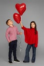 Couple of little girl and boy with red heart balloons Royalty Free Stock Photo