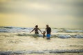 Couple and little son walking relaxed on sunset beach enjoying romantic Summer holidays family trip the parents holding the child Royalty Free Stock Photo