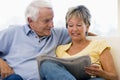 Couple in living room reading newspaper smiling Royalty Free Stock Photo