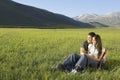 Couple Looking Away While Sitting On Grassy Field Royalty Free Stock Photo