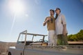 Couple looking away while standing in off road vehicle on landscape Royalty Free Stock Photo