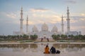 A couple looking at an axial view of the Great Mosque of Abu Dhabi at sunset