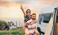 Couple looking camera having fun piggybacking next to their camper van Royalty Free Stock Photo