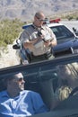 Couple Looking At Each Other With Traffic Cop Writing Ticket Royalty Free Stock Photo