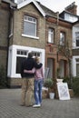 Couple Looking At House With Possessions Outside