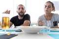 Couple looking at the plate of food in the middle of the table with a fork in hand ready to take salad from a shared plate