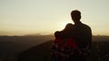 Couple looking sun setting behind mountain. Loving man and woman enjoying sunset Royalty Free Stock Photo