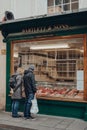 Couple looking at the variety of meat in the window of Barlett & Sons butchery in Bath, UK