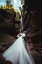 Couple in love against the backdrop of a waterfall. Honeymoon trip. Happy couple in the mountains. Vertical photo of Royalty Free Stock Photo