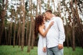 A couple in love beautiful young man and woman are kissing and hugging in a summer park on a sunny day. Date outside, well dressed Royalty Free Stock Photo