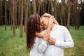 A couple in love beautiful young man and woman are kissing and hugging in a summer park on a sunny day. Date outside, well dressed Royalty Free Stock Photo