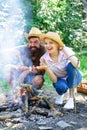 Couple in love camping forest roasting sausage at bonfire. Traditional roasted food as attribute of picnic. Camping and