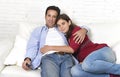 Couple in love cuddling on home couch relaxing watching movie on television with man holding remote control Royalty Free Stock Photo