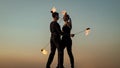 couple in love dance while spinning burning poi blue sky outdoors, fire show