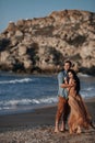 Happy couple in love during honeymoon on a rocky beach near the blue ocean