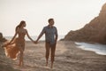 Happy couple in love during honeymoon on a rocky beach near the blue ocean