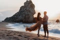 Happy couple in love during honeymoon on a rocky beach near the blue ocean