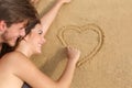 Couple in love drawing a heart on the sand of the beach Royalty Free Stock Photo