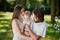 Couple in love dressed in the white casual clothes is spending time in the park in a sunny day with there beautiful baby