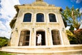 Couple dressed in white, stands in arch of house