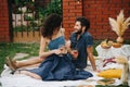 Couple in love, drinking rose wine, having picnic on lawn in their courtyard Royalty Free Stock Photo