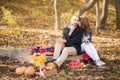 Couple in love in the fall at a picnic. Lovers are kissing, hugging, drinking drink. Steam and pumpkin, yellow leaves, t Royalty Free Stock Photo