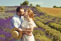 A couple in love in a field of lavender at sunset in good weather. Beautiful woman in a dress and straw panama with a man on the Royalty Free Stock Photo
