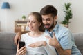 Couple in love or friends sitting on couch using smartphone Royalty Free Stock Photo