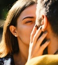 Couple in love is going to kiss. Man and woman with sincere sight on sunny outside background.