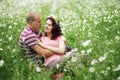 Couple in love guy and girl in a field of white daisies and green grass Royalty Free Stock Photo