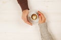 Couple in love holding cup of coffe in hands on wooden background top view, vintage toned image