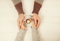 Couple in love holding cup of coffe in hands on wooden background top view, vintage toned image