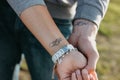 The couple in love holding hand in hand. Paired tattoo initials on the arms