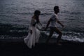 couple in love holding hands running along the beach by the sea Royalty Free Stock Photo