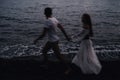 couple in love holding hands running along the beach by the sea Royalty Free Stock Photo